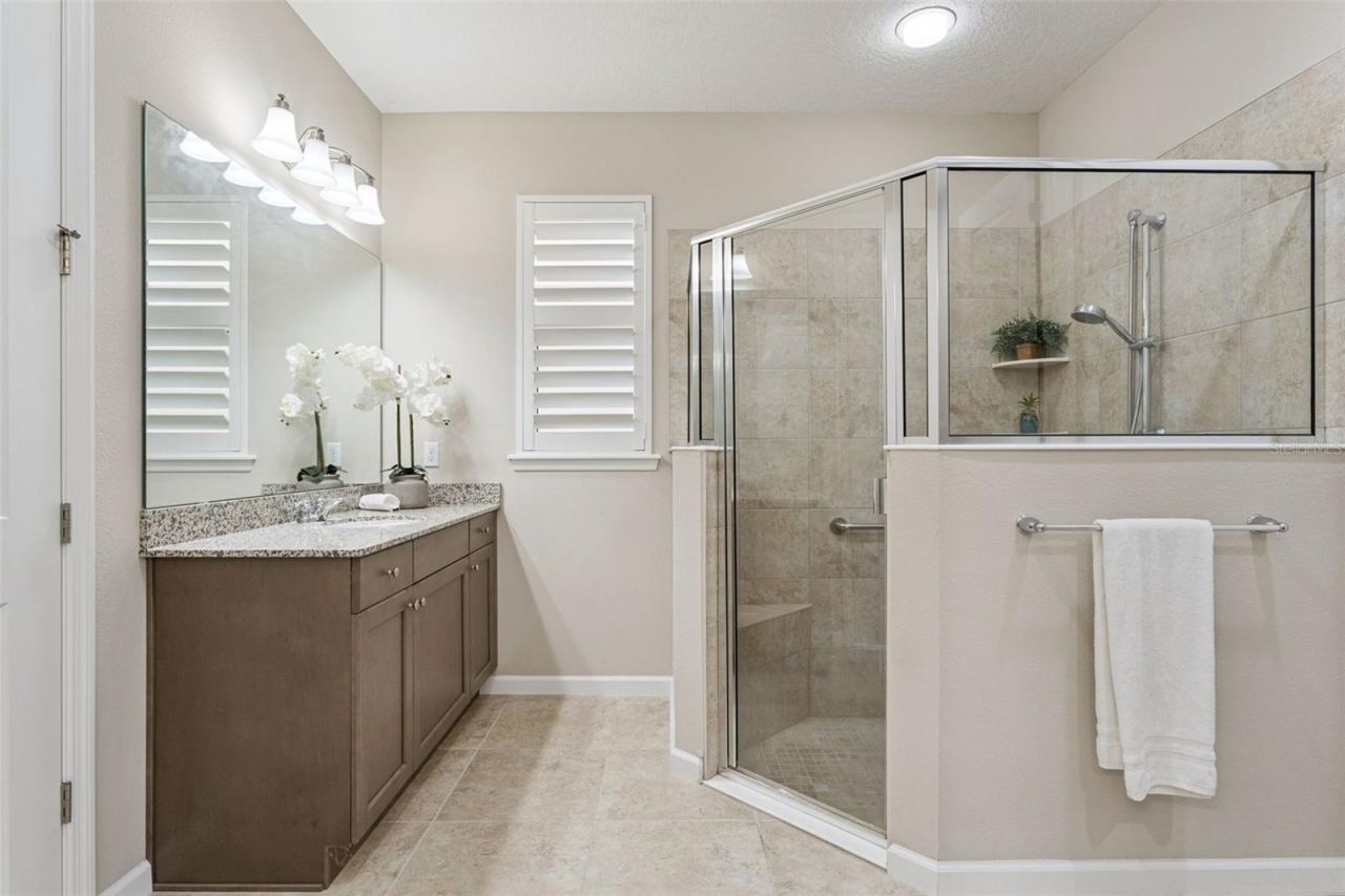 Photo 18 of 20: 13'6" x 11' Primary Bathroom w/ separate granite countertop vanities & a glass enclosed walk-in shower
