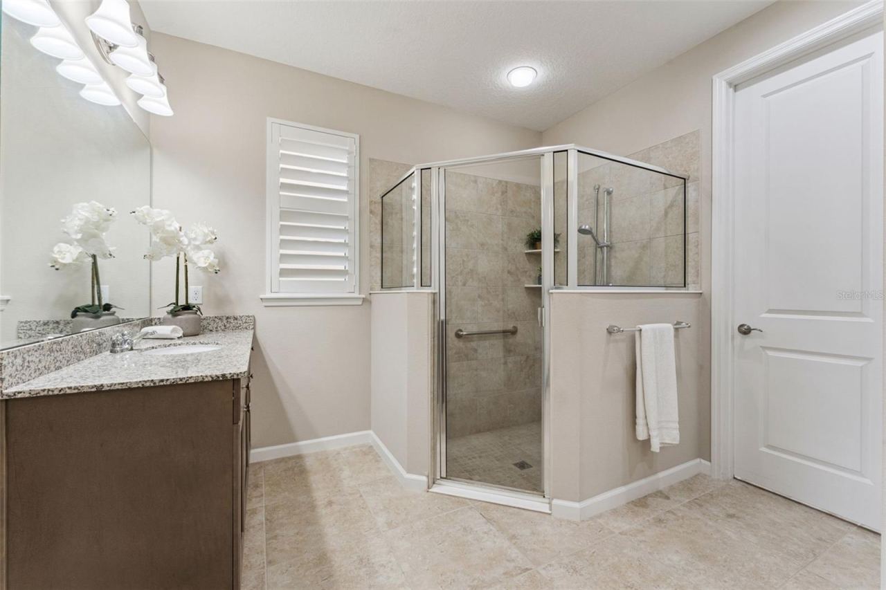 Photo 19 of 20: Primary Bathroom w/ a walk-in shower, bench seat, grab bar, Plantation style shutter & a 14' x 5'6" walk-in closet