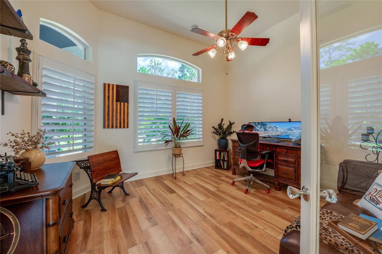 Photo 10 of 20: Bright private office space outfitted with tile flooring, ceiling fan, and large windows with plantation shutters for natural light.