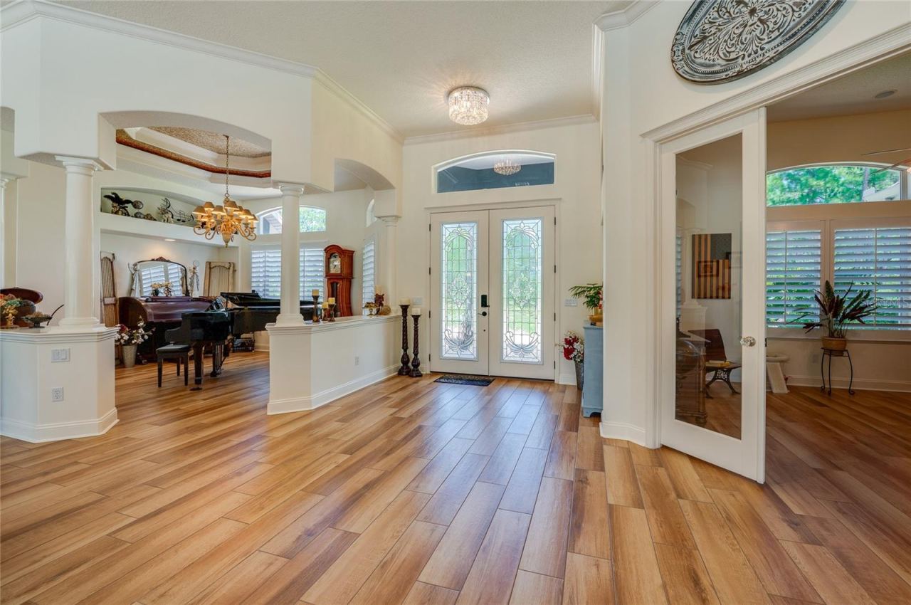 Photo 7 of 20: Welcoming grand entryway featuring double glass front doors, rich tile flooring, recessed lighting, and arched architectural openings.