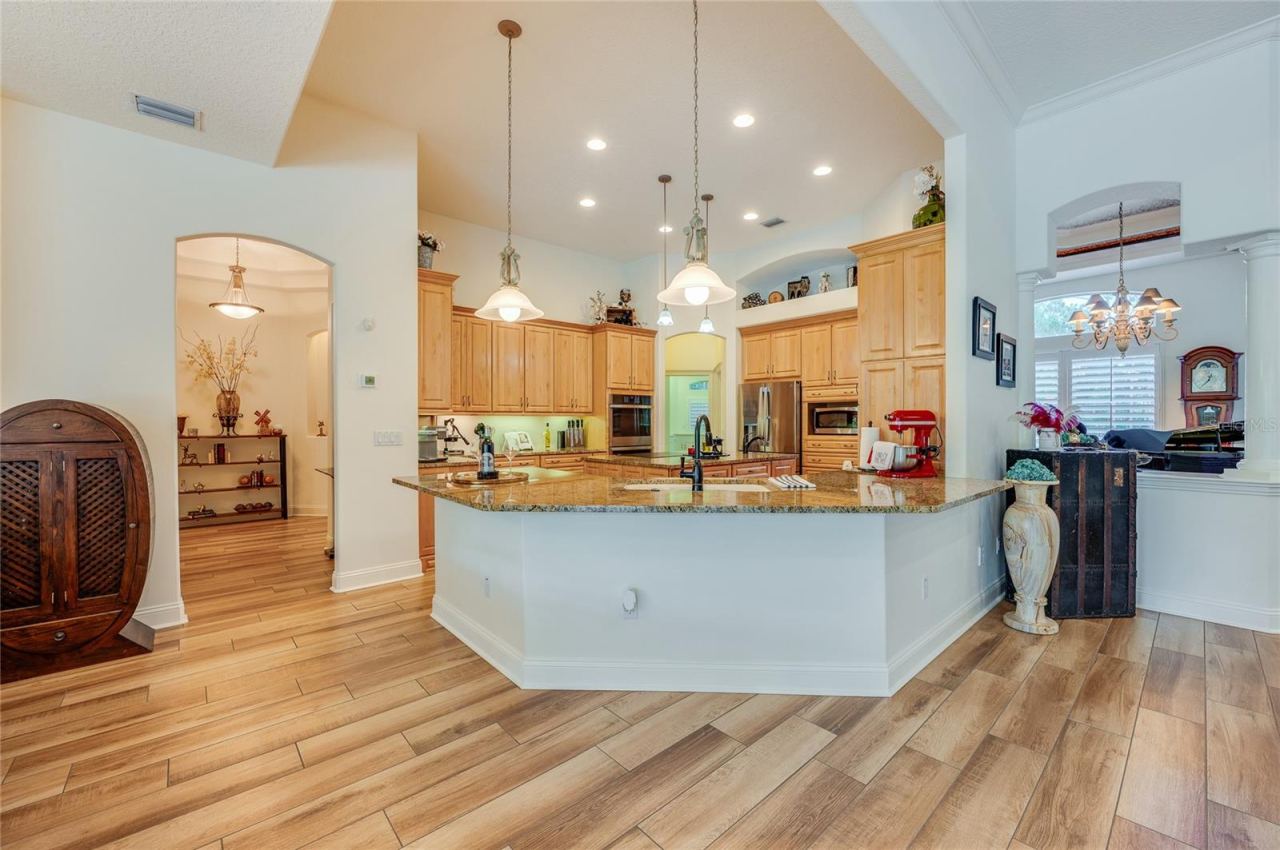 Photo 13 of 20: Gourmet kitchen space showcasing continuous tile flooring, natural wood cabinetry, a raised breakfast bar, and pendant lighting.