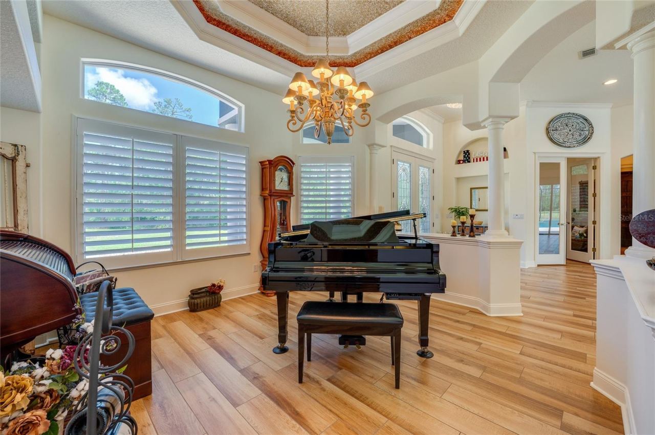 Photo 8 of 20: Elegant formal room accented by warm tile flooring, decorative tray ceilings, an ornate chandelier, and classic shuttered windows.