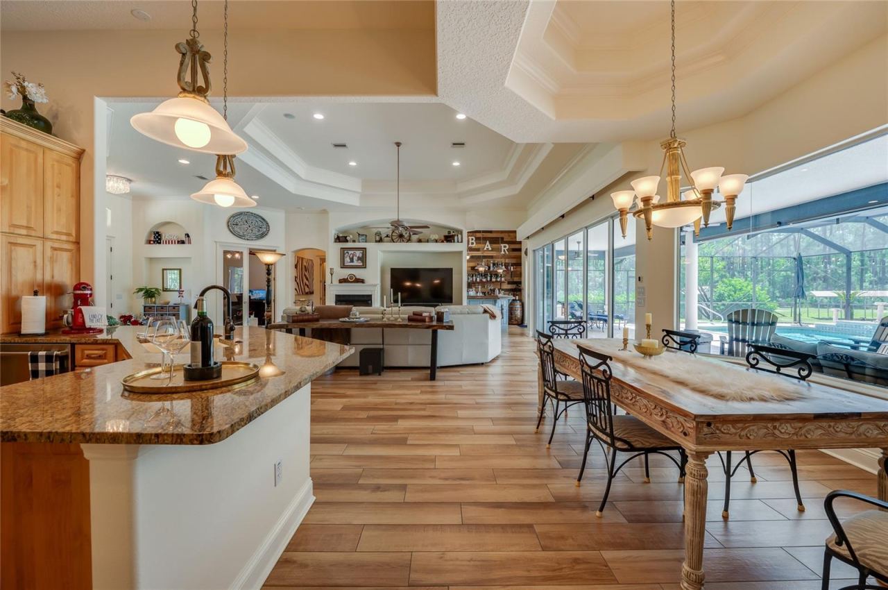 Photo 17 of 20: Open-concept living space linking the kitchen counter and dining area to the adjacent living room with direct pool views through expansive glass doors.