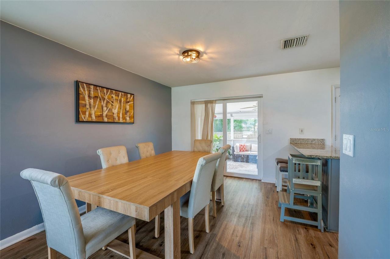 Photo 9 of 20: Light-filled dining area featuring LVP flooring, accent wall paint, and sliding glass doors that lead directly out to a covered patio space.