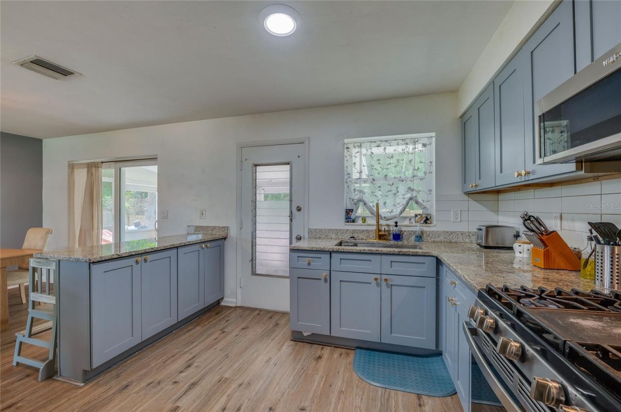 Photo 13 of 20: Well-appointed kitchen setup complete with an electric range stove, stainless steel appliances, granite counters, and direct outdoor access.