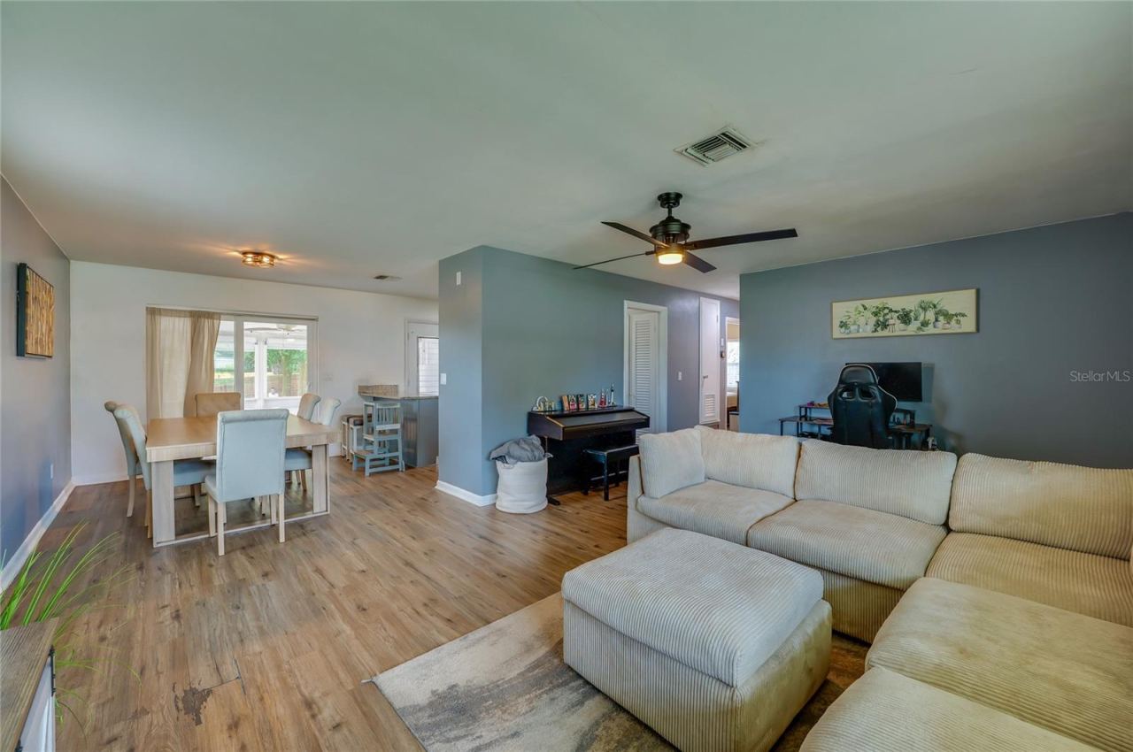 Photo 8 of 20: Broad view of an open layout emphasizing natural LVP floors, a ceiling fan, and clear sightlines between living and dining spaces.