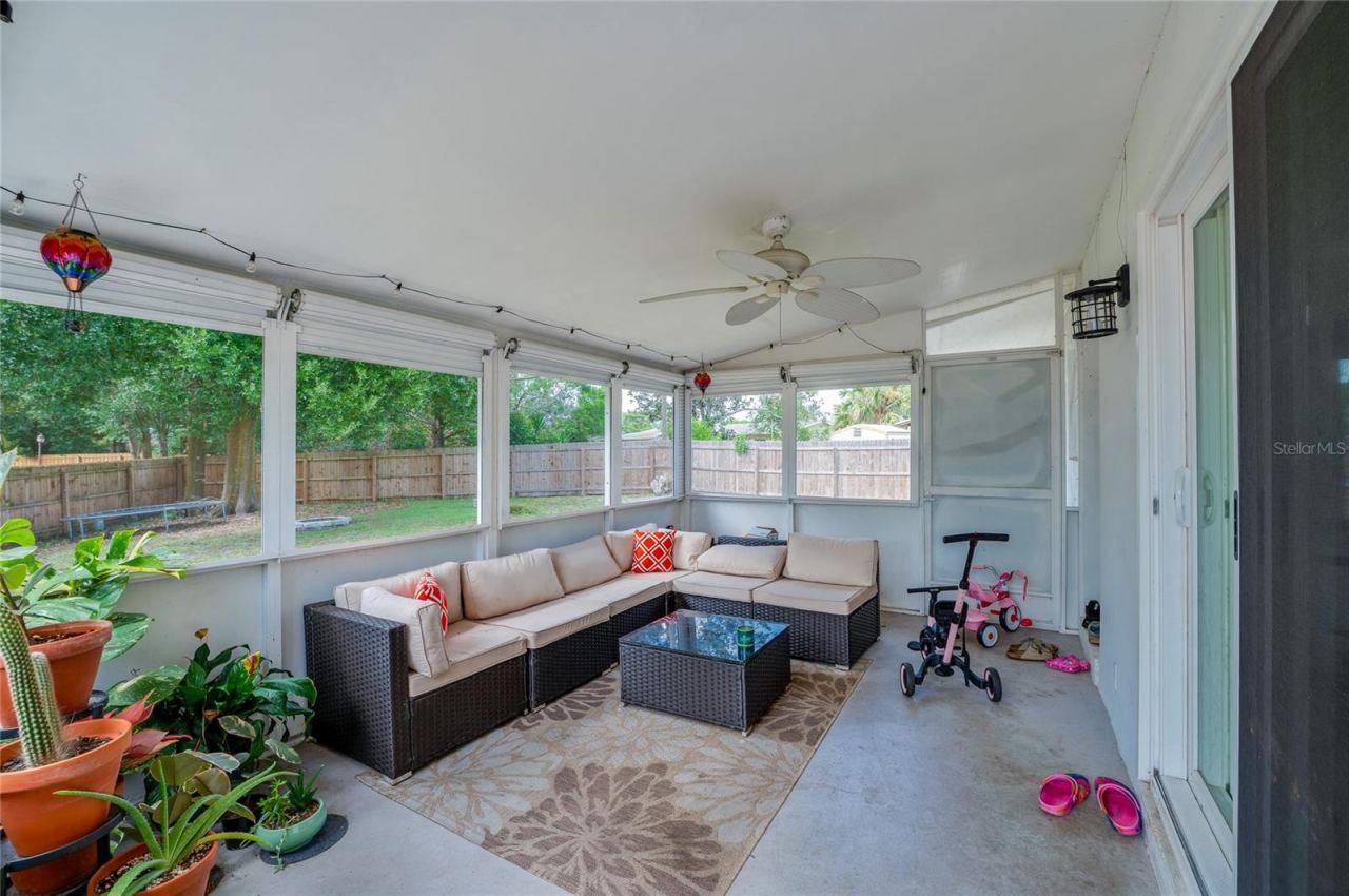 Photo 14 of 20: Enclosed, screened-in porch with ceiling fans and surrounding mesh screens overlooking the fenced backyard area.