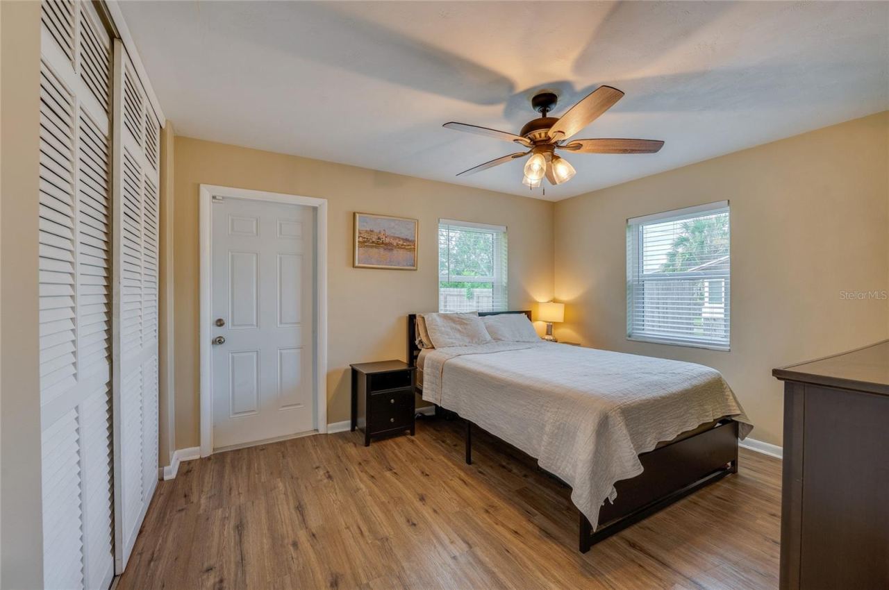 Photo 16 of 20: Cozy bedroom offering LVP flooring, louvered closet doors, neutral walls, and a ceiling fan with integrated lighting.