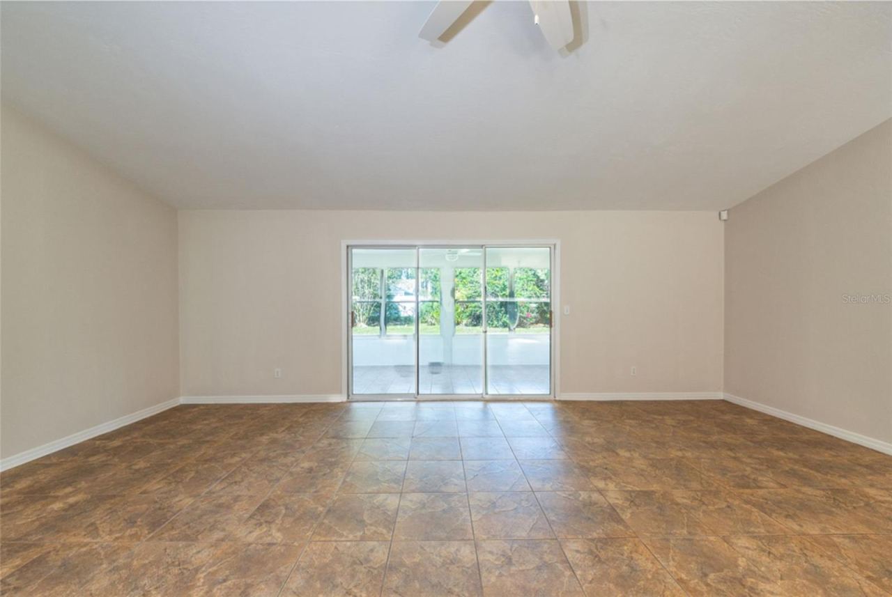 Photo 7 of 20: Living room looking towards the 200 sf Florida room. Triple sliders let in so much natural light.