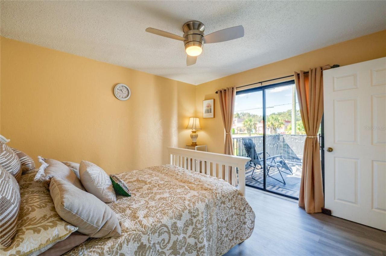 Photo 18 of 20: Bright room with LVP flooring, a modern ceiling fan, and sliding glass door access to a private balcony.