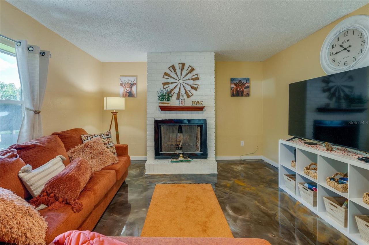 Photo 8 of 20: Cozy living room space centered around a painted white brick fireplace and hearth with large windows allowing for ample natural light.