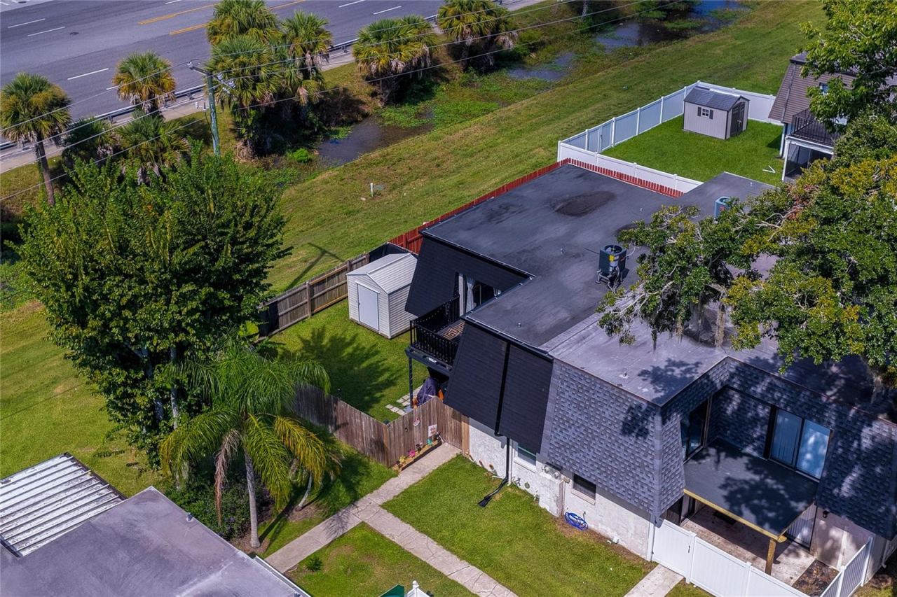 Photo 3 of 20: Aerial view of a residential property surrounded by lush greenery, featuring fenced yard space, storage shed, and a balcony.