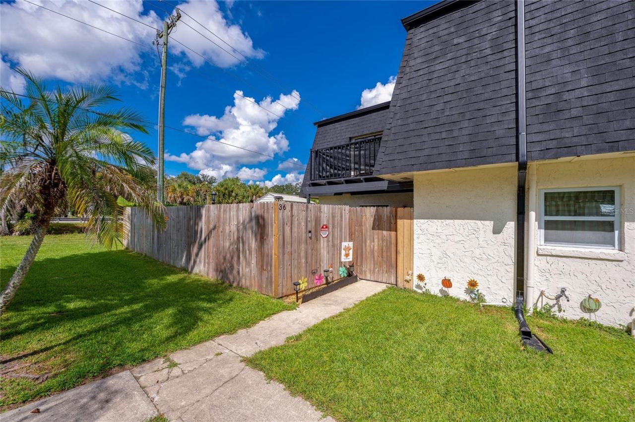 Photo 2 of 20: Exterior entry pathway guided by a wooden privacy fence.