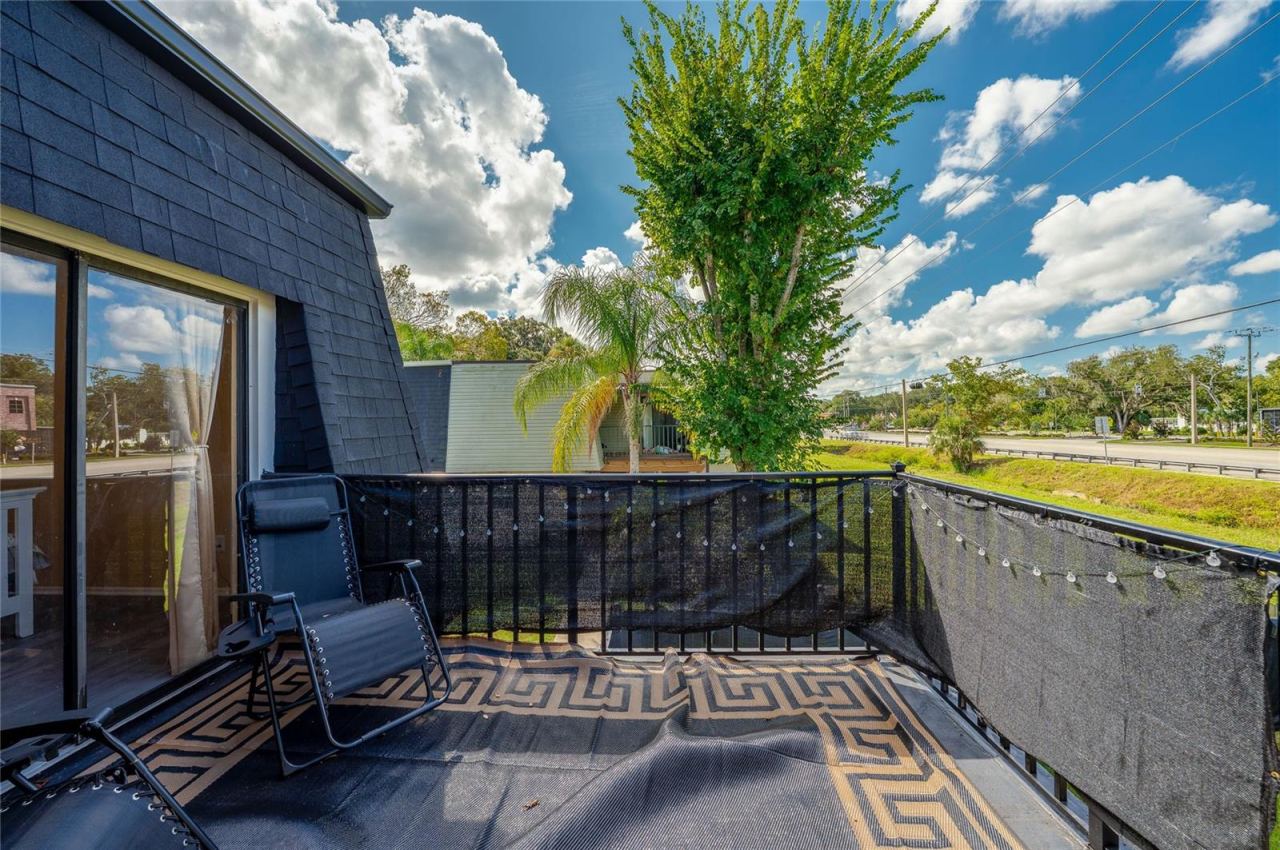 Photo 19 of 20: Private upper-level balcony featuring black mesh privacy screening, a patterned floor mat, and open views of surrounding green space.