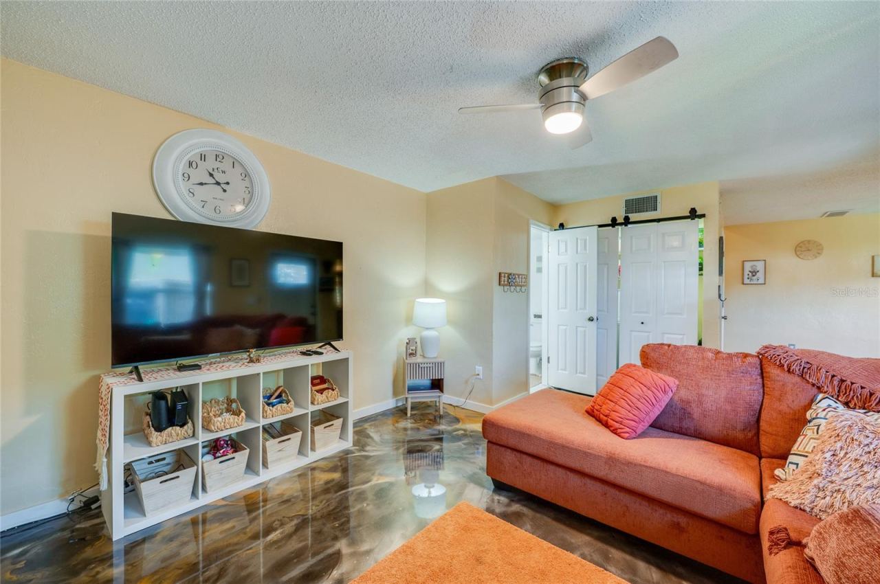 Photo 7 of 20: Inviting living space highlights striking epoxy floor finishes, a ceiling fan, and white sliding barn doors for a modern touch.