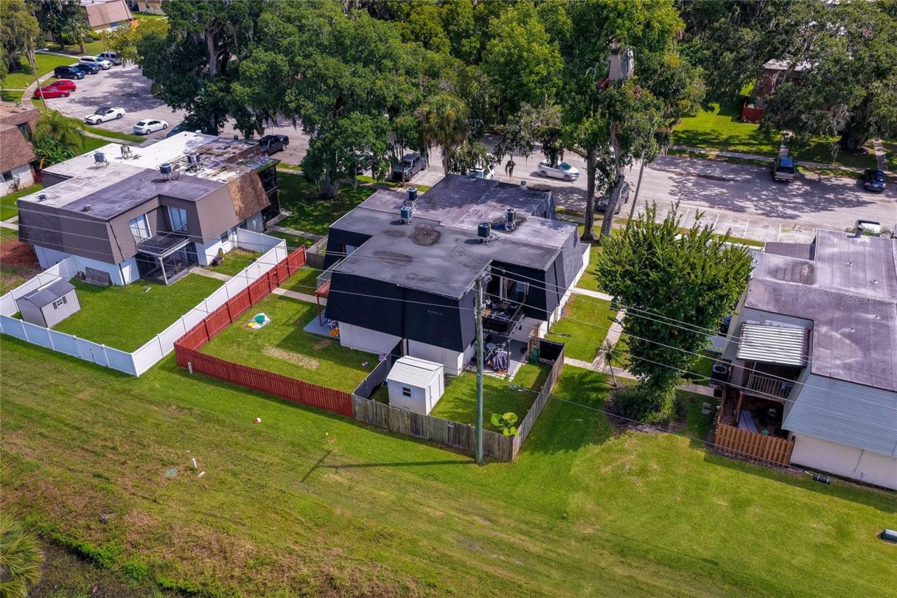Photo 4 of 20: Elevated aerial view of the residential unit emphasizing its private yard, roofline layout, and mature surrounding trees.