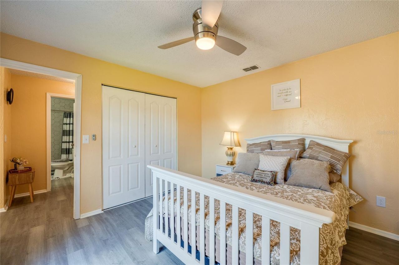 Photo 17 of 20: Light-filled room featuring LVP flooring, modern ceiling fan, and sliding closet doors.