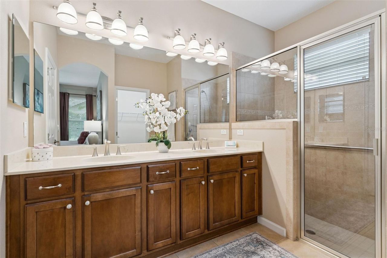 Photo 19 of 20: Primary Bathroom w/ dual sinks, glass enclosed walk-in shower, built-in bench seat & a grab bar