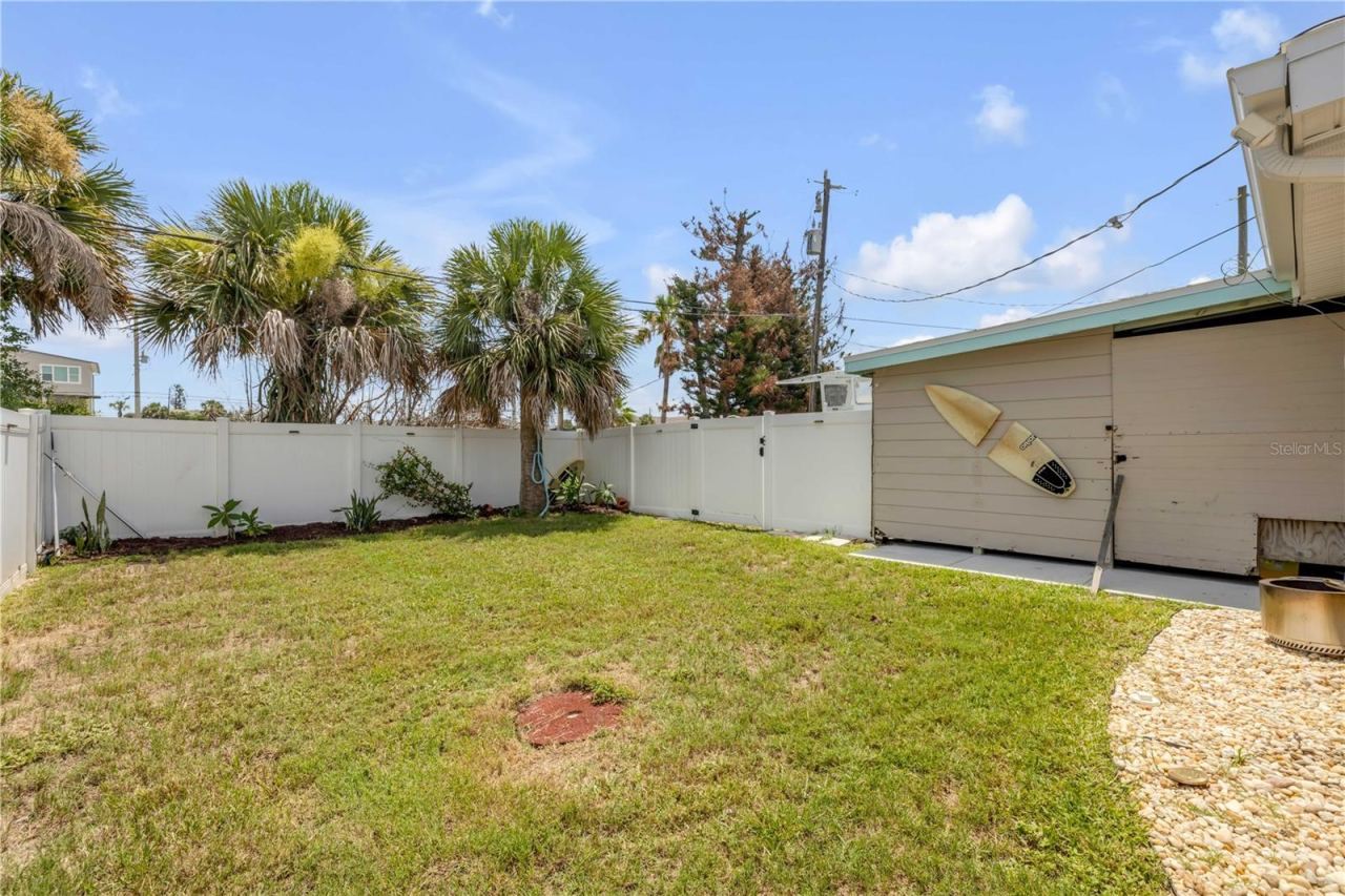 Photo 19 of 20: Fenced yard with lawn and detached outbuilding.