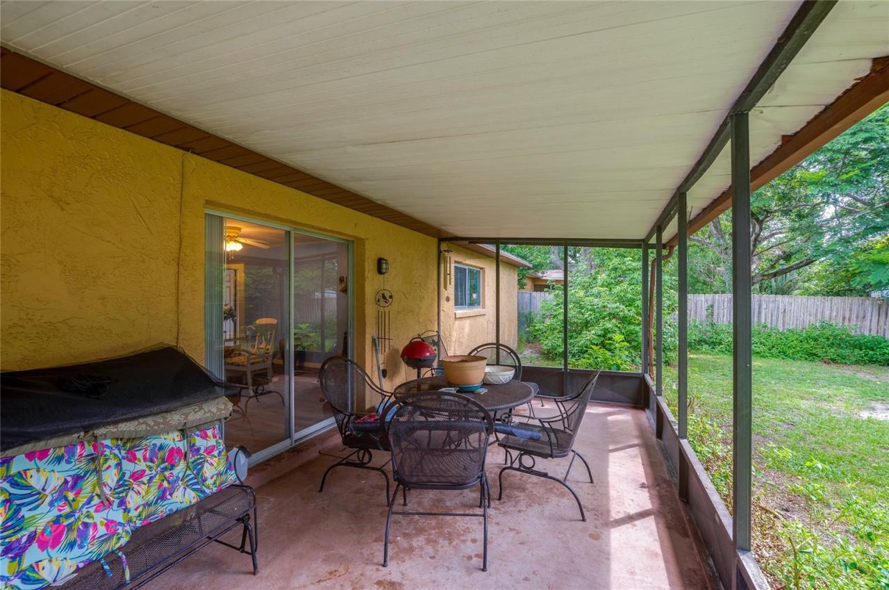 Photo 12 of 20: Covered, screened outdoor patio space with concrete flooring and sliding door access to the main interior.