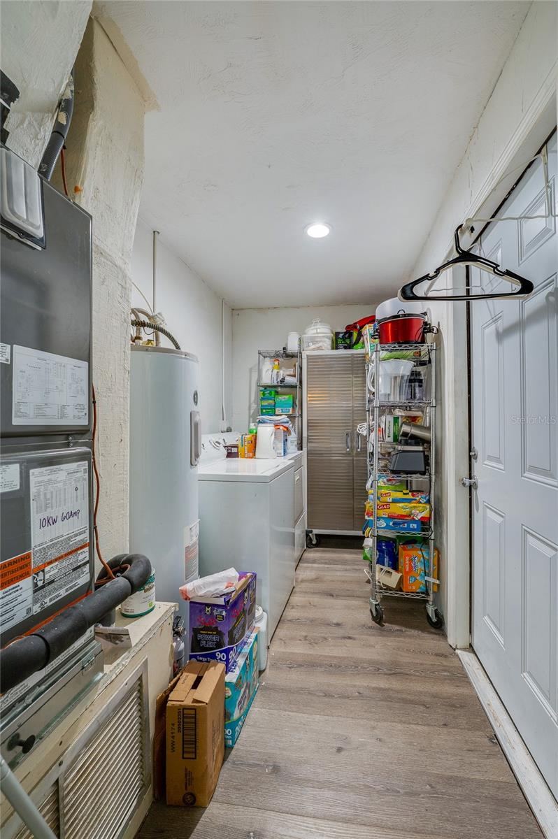 Photo 20 of 20: Utility and laundry corridor featuring LVP flooring, white cabinetry storage, and dedicated space for a washer and dryer.