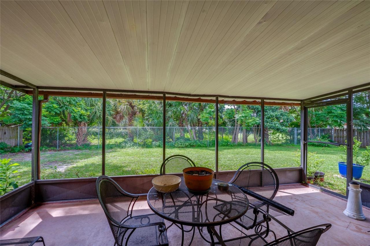 Photo 11 of 20: Screened-in back porch providing full views of the green backyard and surrounding tree line.