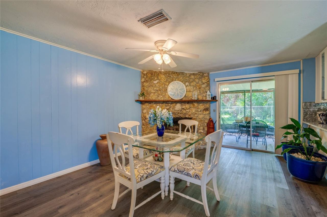 Photo 8 of 20: Inviting space highlighted by a floor-to-ceiling stone fireplace, light blue paneling, LVP flooring, and direct sliding glass door access to the back patio.