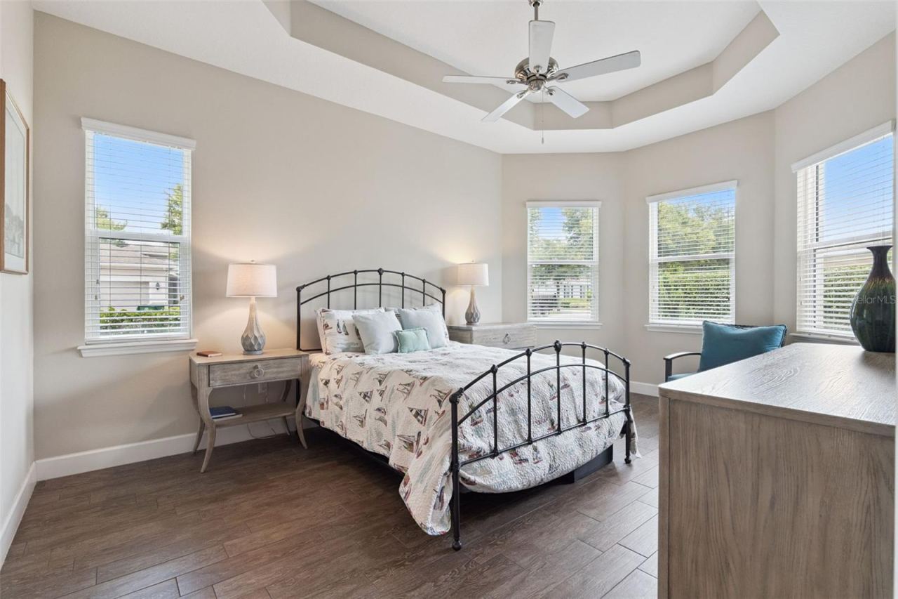 Photo 15 of 20: 12' x 17'6" Primary Bedroom w/ porcelain plank tile, tray ceiling, a ceiling fan & view to the private backyard