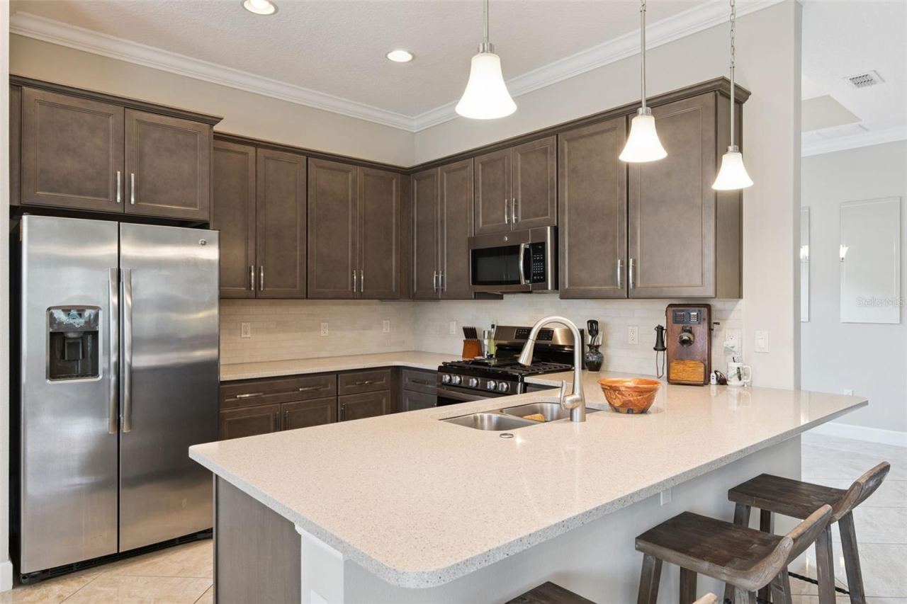 Photo 9 of 20: Kitchen breakfast bar w/ pendant lighting above & tumble stone backsplash underneath Kitchen cabinets