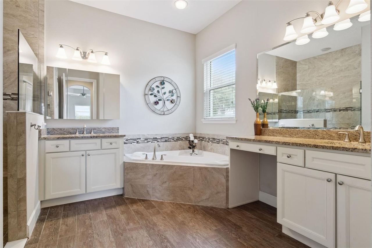 Photo 18 of 20: 12' x 11' Primary Bath w/ separate vanities, glass enclosed walk-in shower w/ bench seat & corner soaking tub