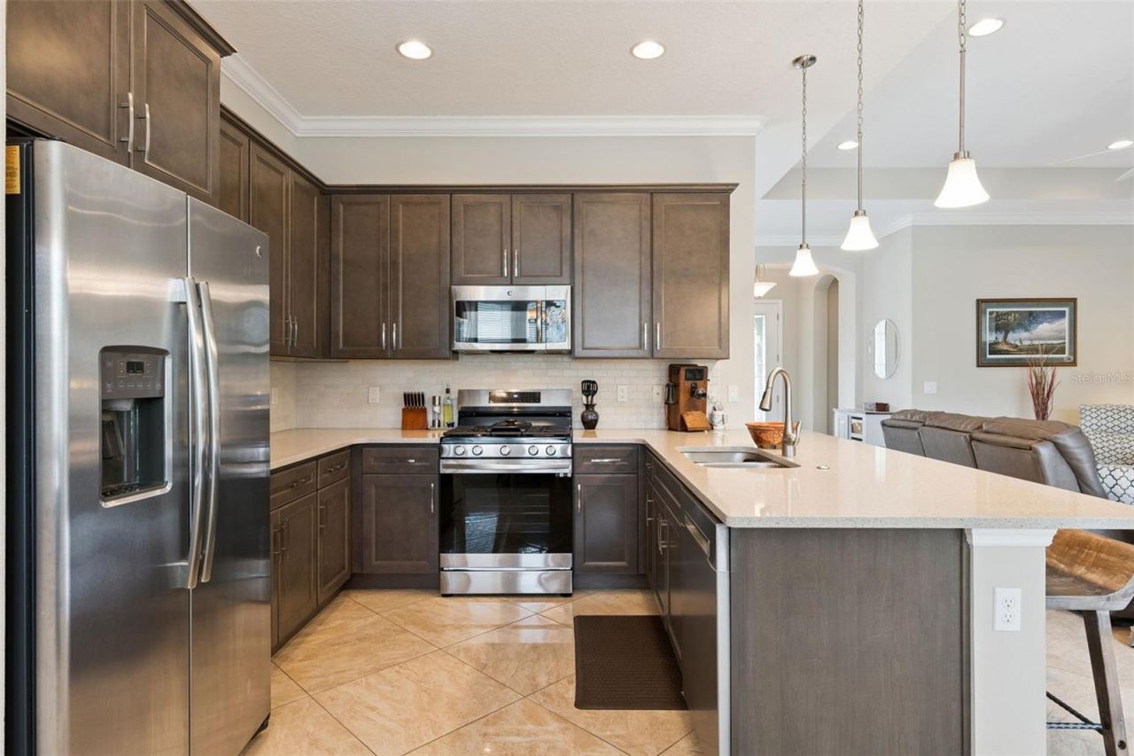 Photo 10 of 20: 11'6" x 13'6" Kitchen w/ stainless steel appliances, quartz countertops, stone backsplash & a convection natural gas range