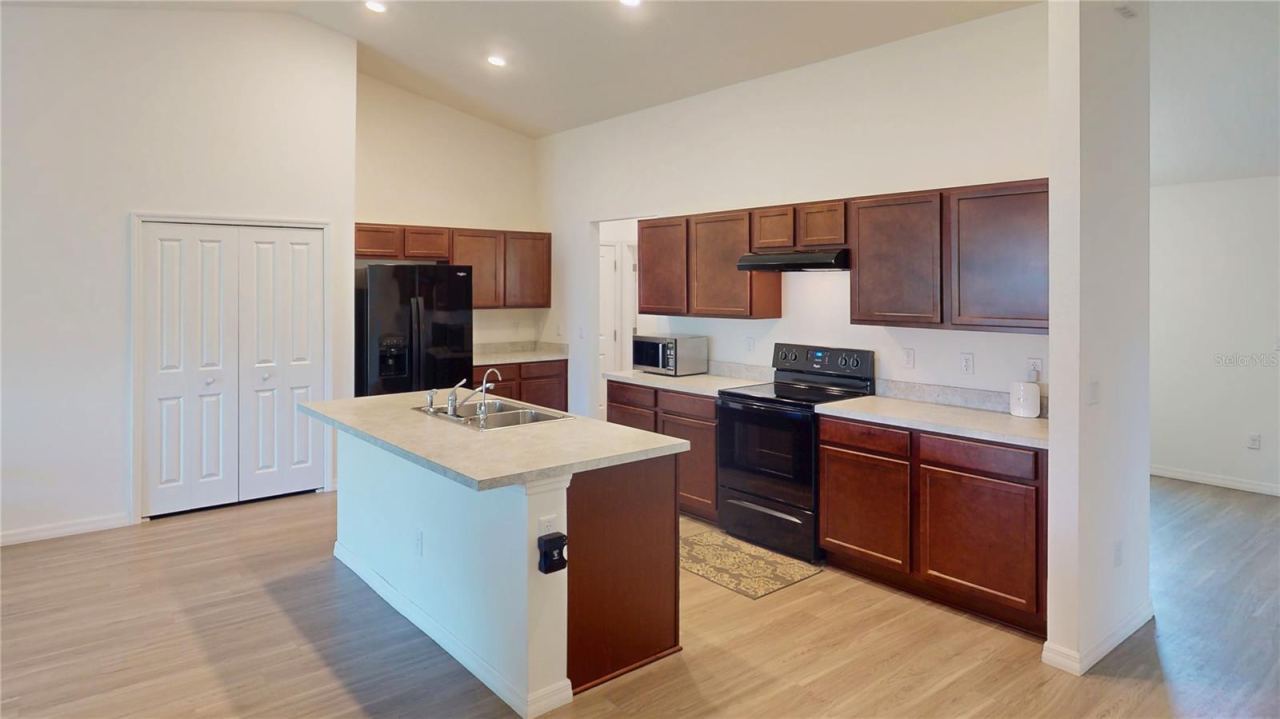 Photo 10 of 20: Open, modern kitchen with a large center island and sink, generous cabinet space, and a clean, functional layout—perfect for meal prep, casual seating, and easy flow into the main living areas.