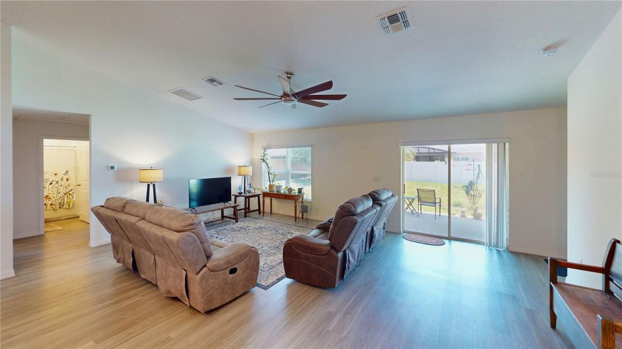 Photo 7 of 20: Spacious living room with clean sightlines, modern ceiling fan, and durable flooring—plus sliding glass doors that bring in natural light and open to the backyard for easy indoor-outdoor living.