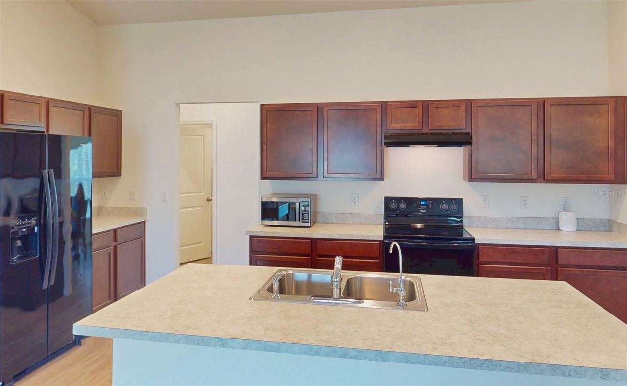 Photo 12 of 20: Still the kitchen, but put emphasis on this center island that you can also eat at. It's like a breakfast bar and it overlooks the living room and out onto the yard. It's something like that.