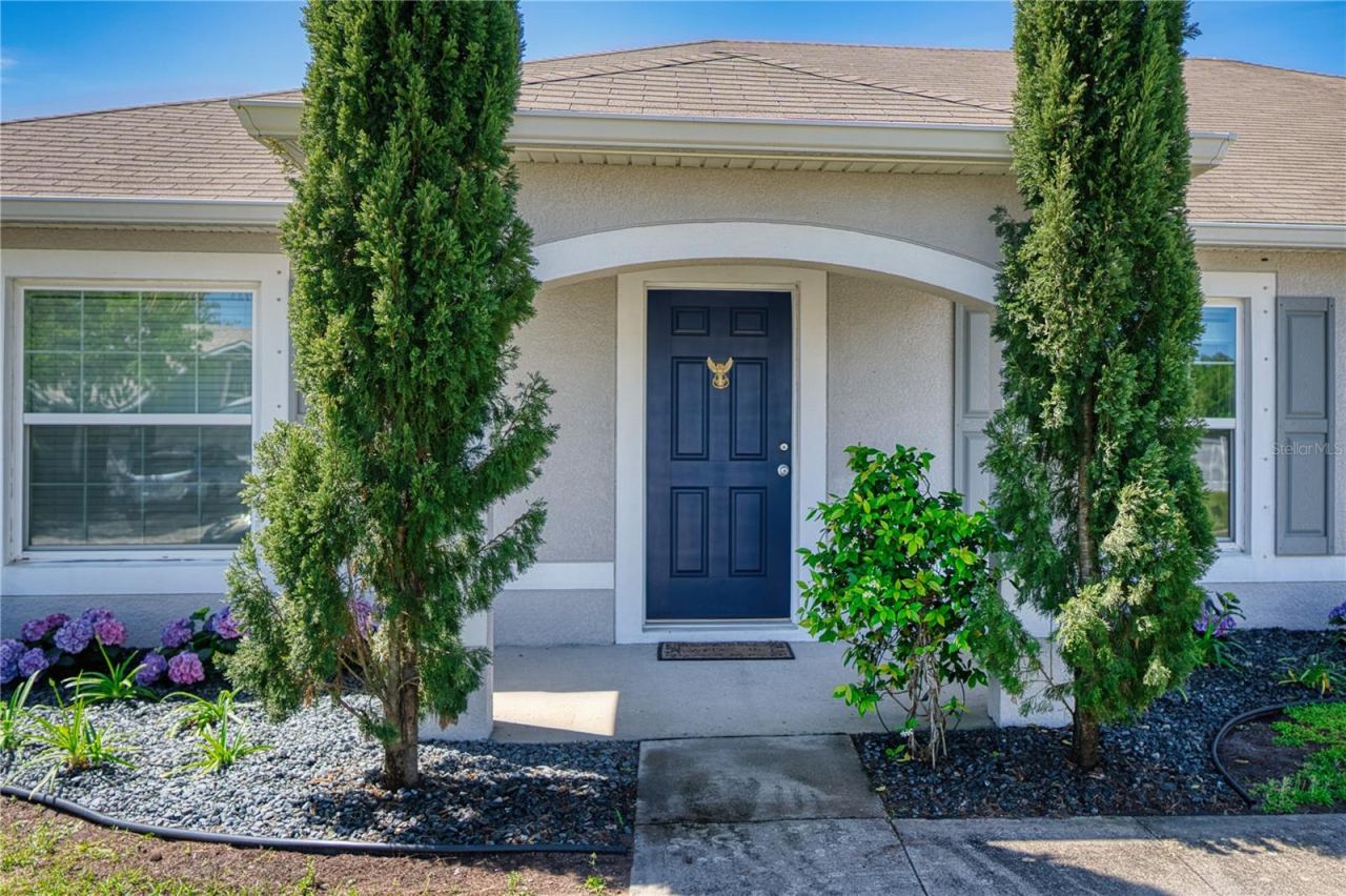 Photo 6 of 20: Handsome covered entryway with a graceful arch, framed by tall accent landscaping and a striking front door, creating a refined focal point and an inviting sense of arrival.