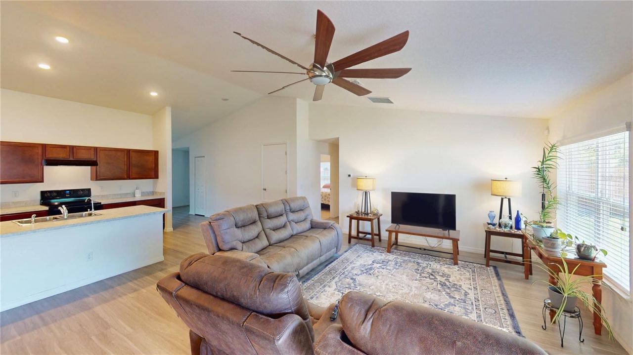 Photo 14 of 20: Open-concept view showing how the kitchen flows right into the family room—perfect for staying connected while cooking—plus a clear line toward the guest suite for a smart, split layout that gives visitors their own space.
