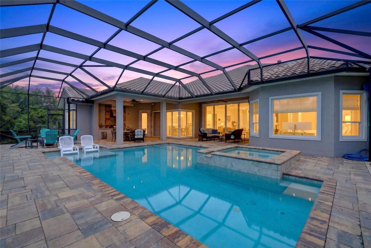 Photo 2 of 20: This is where Florida living takes over—sunny afternoons in the pool, relaxing in the spa, and evenings entertaining by the outdoor kitchen, all with a peaceful water view as your backdrop.