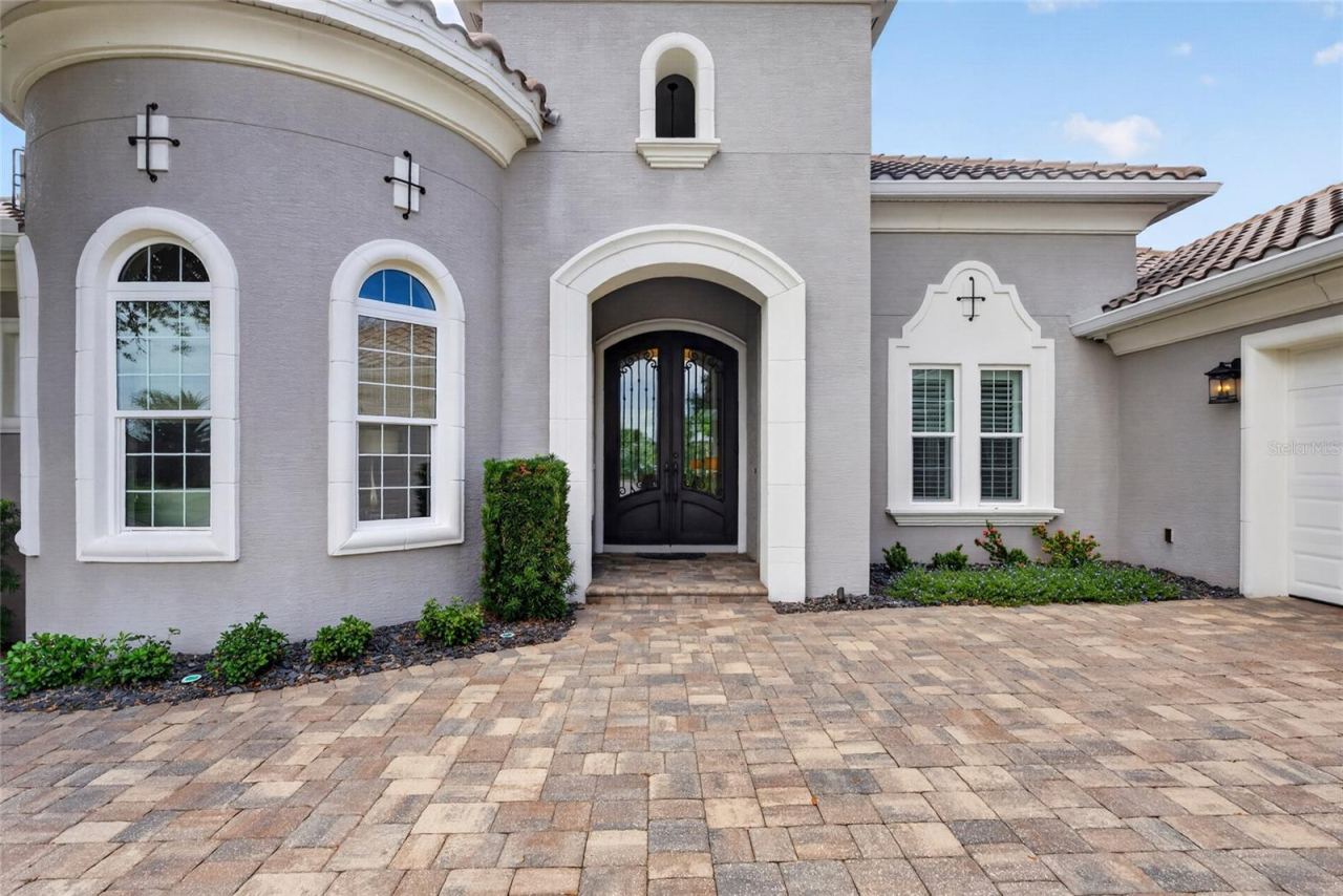 Photo 12 of 20: Mediterranean-inspired architecture, graceful arched windows, a tile roof, and an expansive paver drive create undeniable curb appeal—an impressive introduction to the luxury and craftsmanship found within.