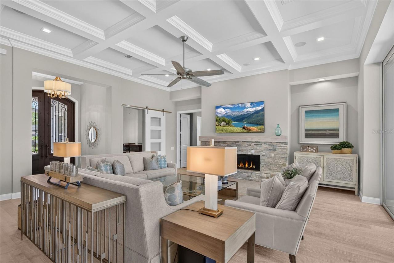 Photo 15 of 20: Architectural artistry takes center stage here—the dramatic coffered ceiling and sleek stone fireplace bring depth and character to a great room made for fireside nights and unhurried conversation.