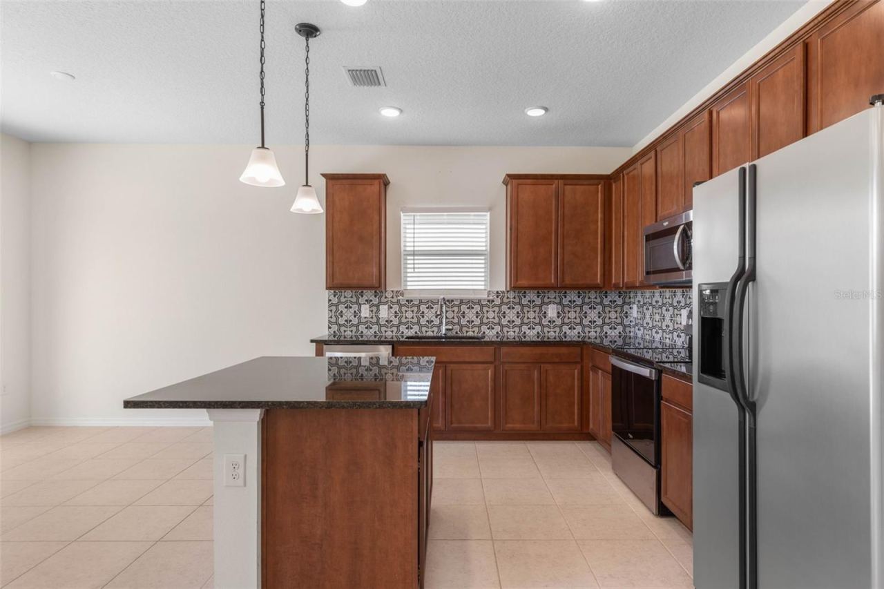 Photo 18 of 20: Warm, welcoming kitchen anchored by a kitchen island and designed for both cooking and connection.