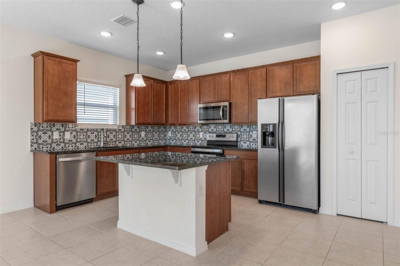 Photo 3 of 20: Kitchen area with warm cabinetry, stainless steel appliances, and a center island for casual dining