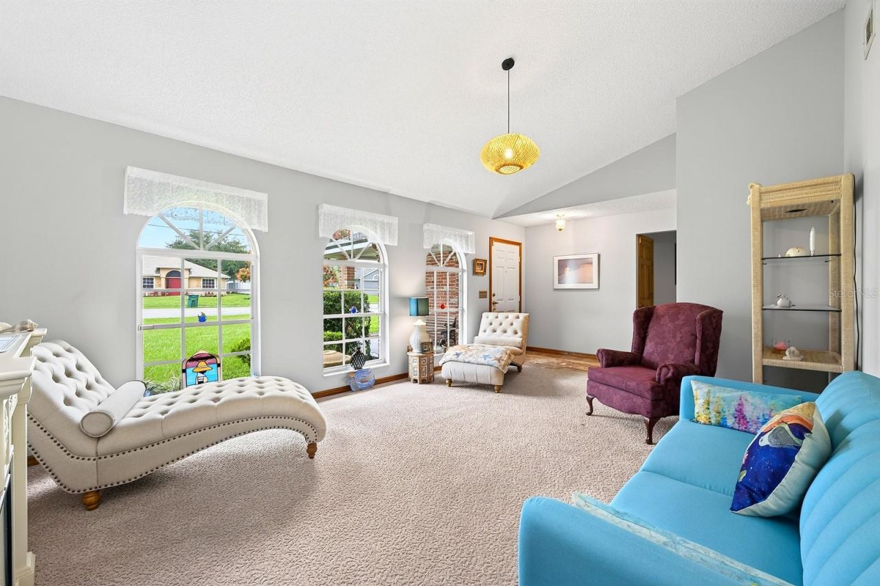 Photo 4 of 20: Step inside to a formal Living Room featuring plush carpeting and three ELEGANT ARCHED WINDOWS that fill the space with natural light.