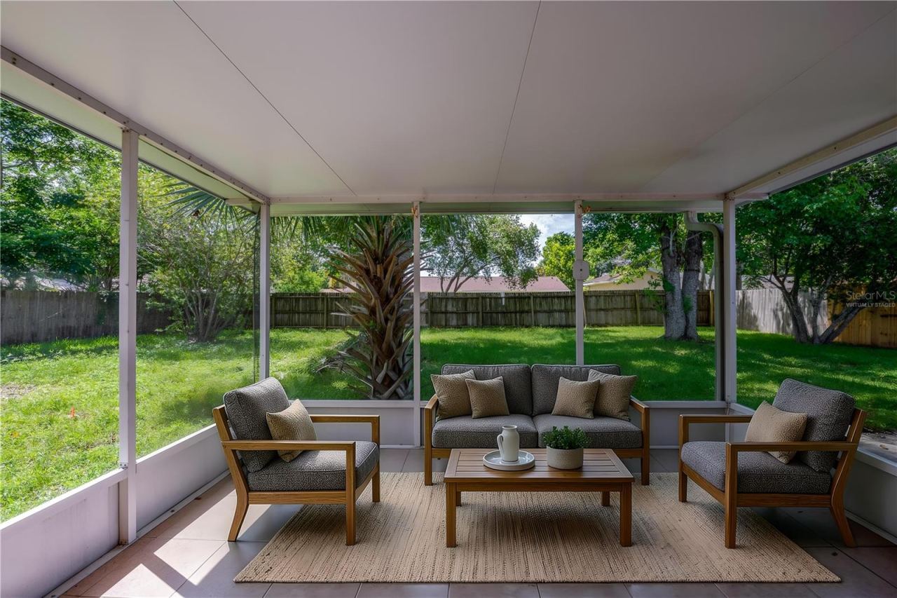 Photo 17 of 20: Virtually Staged. Enclosed screened porch featuring neutral tile flooring, a solid covered ceiling, and floor-to-ceiling screens overlooking a spacious, grass-covered backyard framed by mature trees and a wooden privacy fence.