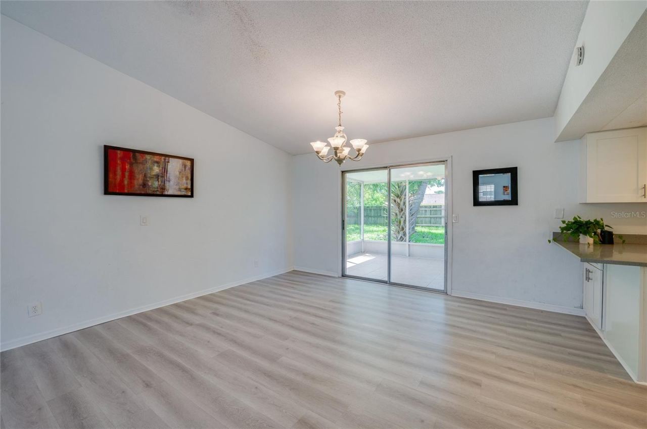 Photo 10 of 20: Inviting dining area featuring an elegant chandelier, light luxury vinyl flooring, and direct access to a screened porch via sliding glass doors. An adjoining counter offers a convenient pass-through connection to the kitchen.