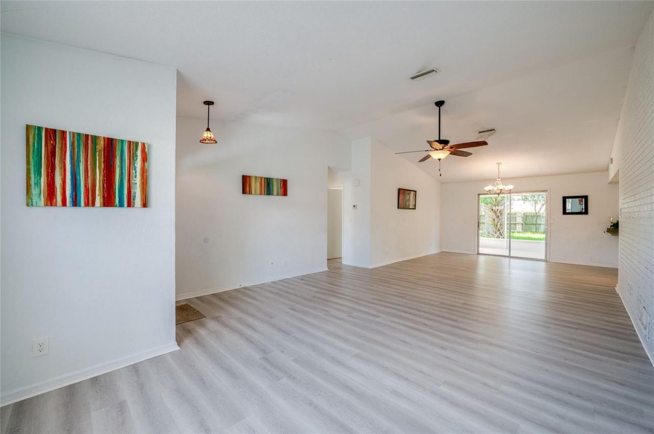 Photo 7 of 20: Bright interior space featuring light luxury vinyl floors, vaulted ceilings, and hanging light fixtures. The open layout seamlessly connects the entry area to the main living and dining spaces.