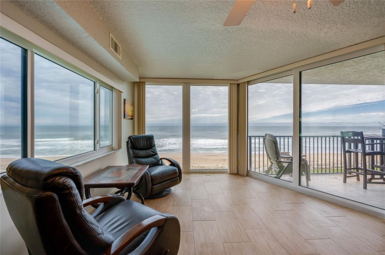 Photo 10 of 20: A light-filled corner retreat with panoramic ocean views through wraparound windows. This flexible space is perfect for morning coffee, reading, or enjoying the serene beachfront setting.