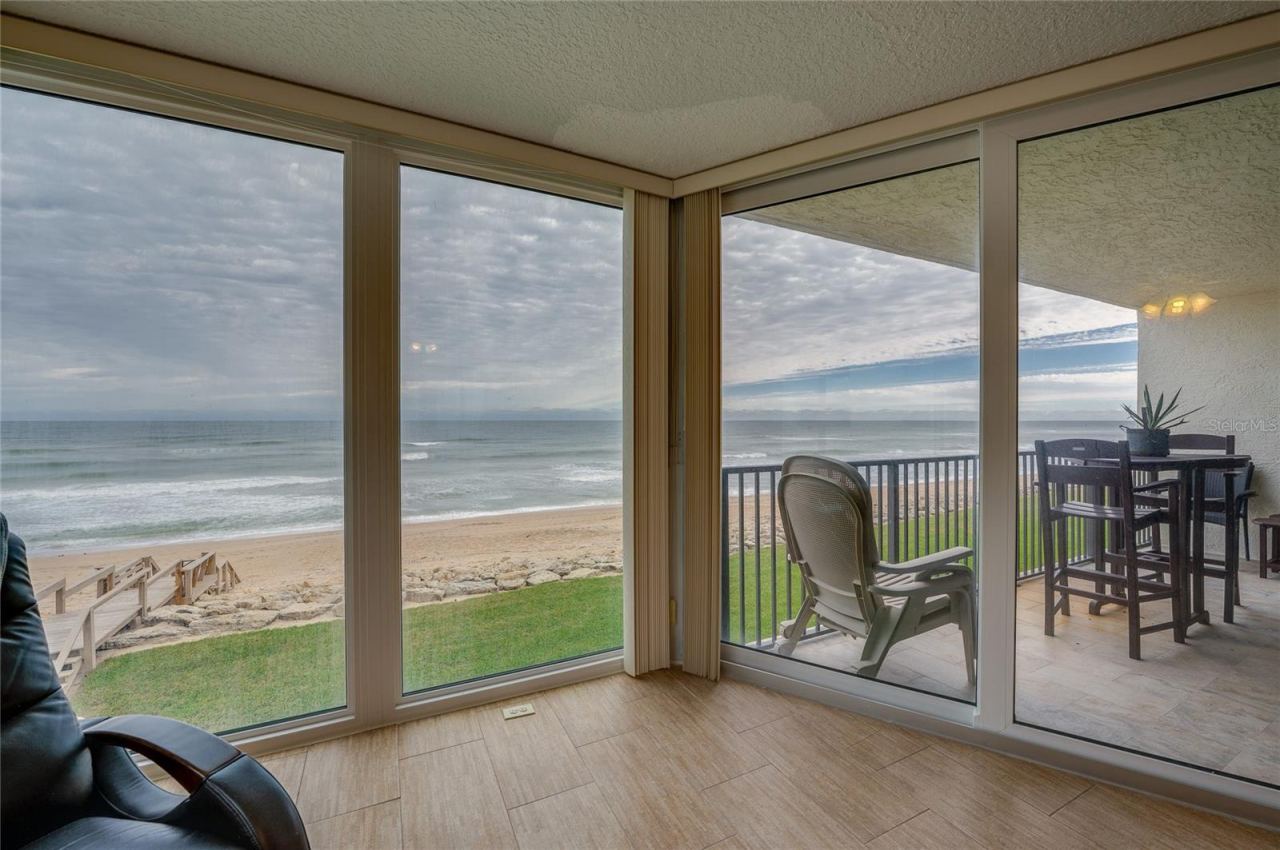 Photo 11 of 20: Expansive glass doors open directly to the covered balcony, creating seamless indoor-outdoor flow and capturing stunning views of the sand and surf.