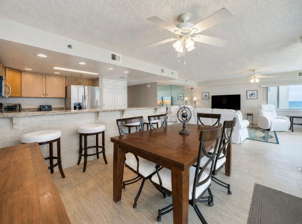 Photo 14 of 20: A central dining area connects to the kitchen and living space, all under ceiling fans and surrounded by windows—ideal for casual meals and gatherings.