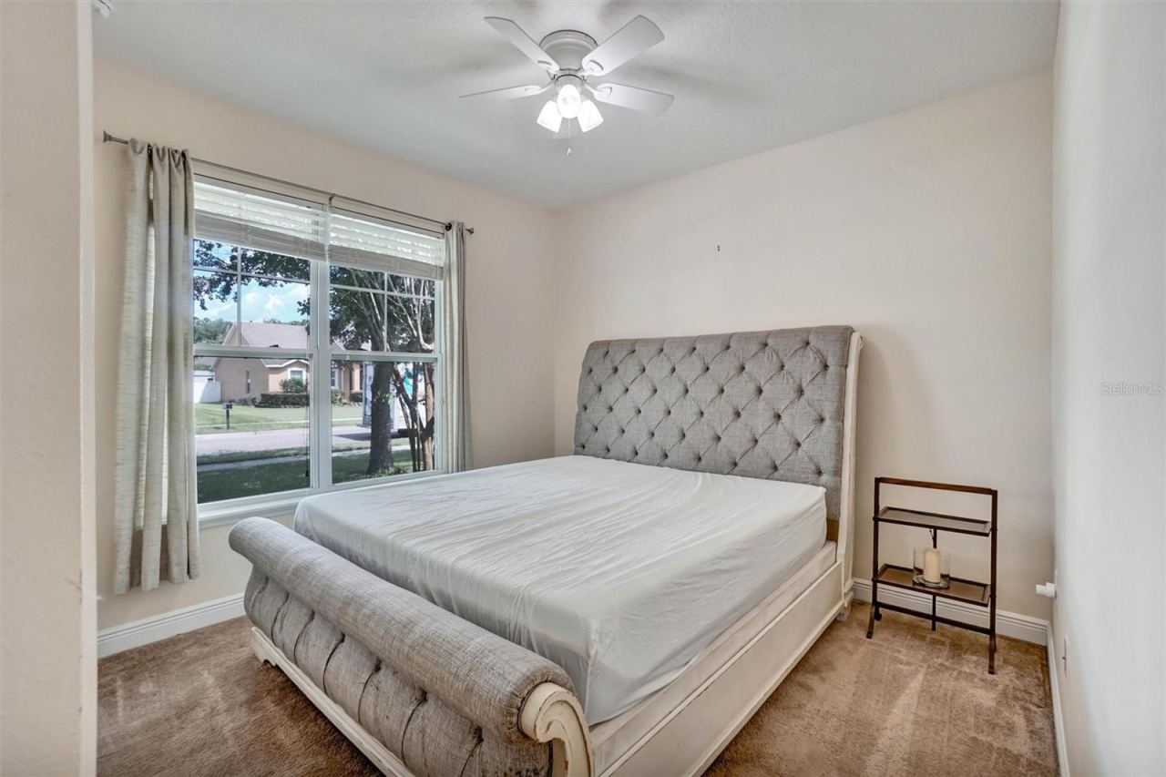 Photo 16 of 20: Second BedroomBright bedroom with a ceiling fan, carpeted flooring, and a large window
