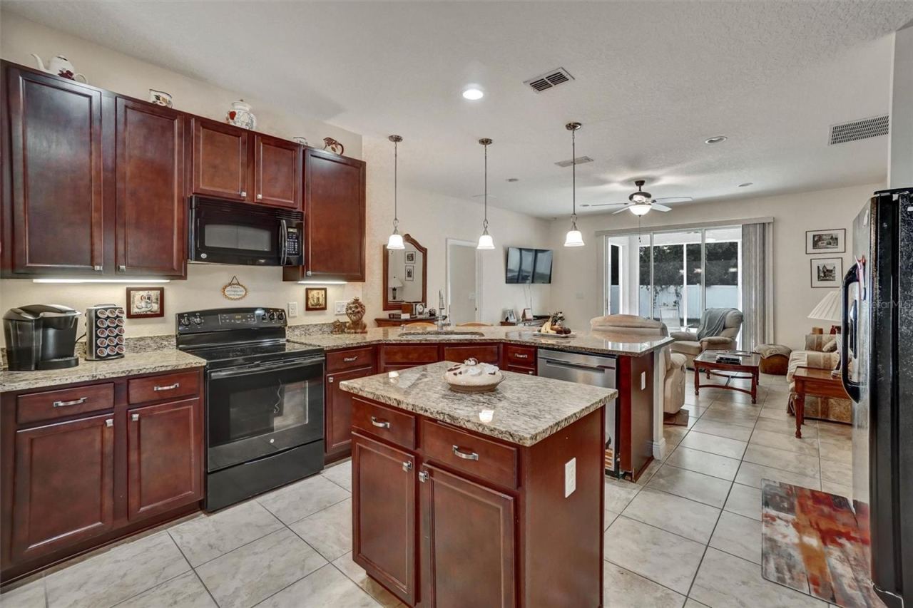 Photo 8 of 20: Kitchen IslandSpacious kitchen featuring granite countertops, wood cabinetry, and a center island.
